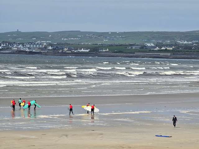 lots of white water as a few beginner surfers make their way into the water